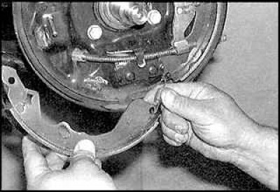 6. Отсоедините верхнюю возвратную пружину от передней тормозной колодки.