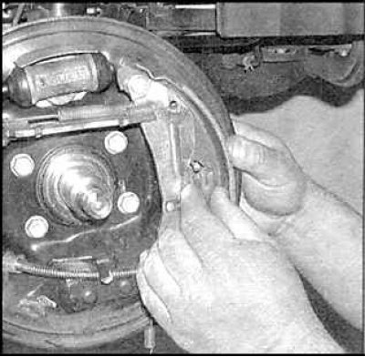 7. Отсоедините регулятор и нижнюю возвратную пружину от передней тормозной колодки.