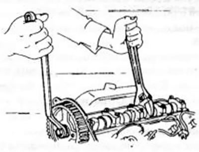 Рис. 37. Освобождение болтов приводного колоса распределительного вала.